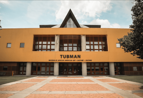 Exterior view of the Tubman Museum of African American Art in a modern building with orange and gray features.
