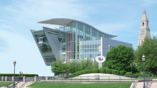 Modern building with a unique, angular design, surrounded by greenery and a clear blue sky.
