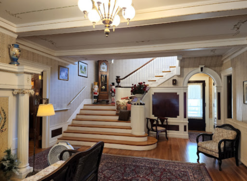 A spacious, elegant foyer with a staircase, vintage decor, and a cozy seating area.