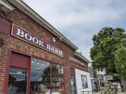 Exterior of a brick building with a sign reading "Book Barn" and a nearby tree, under a cloudy sky.