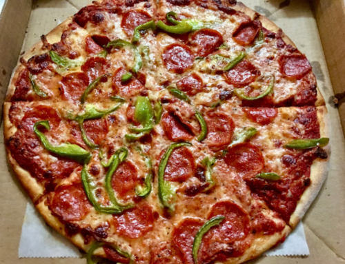 A large pizza topped with pepperoni and green bell peppers, in a pizza box.