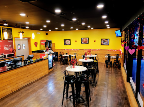 A cozy restaurant interior with yellow walls, tables, and heart decorations, creating a warm atmosphere.