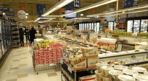 A grocery store aisle filled with various food products, including fruits, snacks, and refrigerated items.