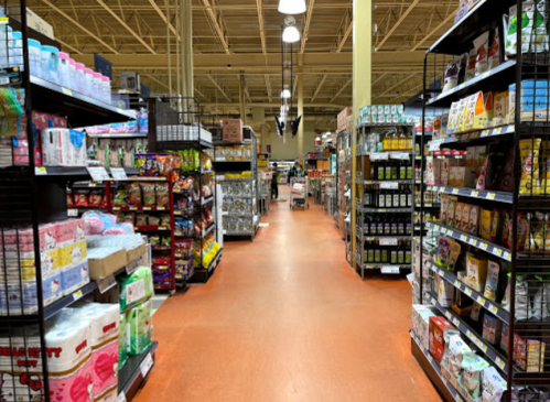 A grocery store aisle filled with various products on shelves, including snacks, beverages, and household items.