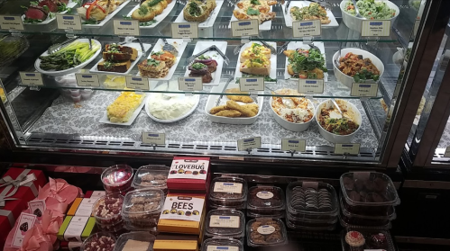 A display case filled with various dishes and desserts, including salads, entrees, and sweets.