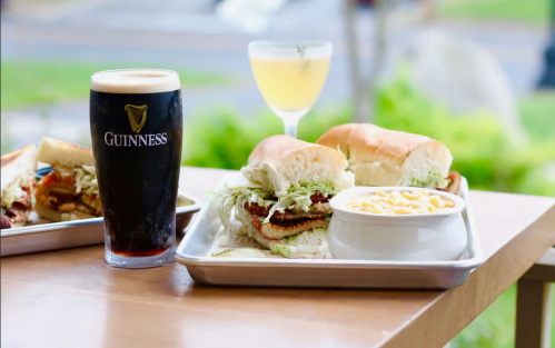 A tray with a pint of Guinness, a cocktail, a sandwich with lettuce, and a bowl of macaroni and cheese.