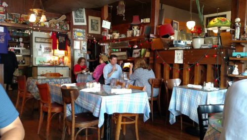Cozy restaurant interior with wooden tables, colorful decor, and patrons enjoying their meals in a warm atmosphere.