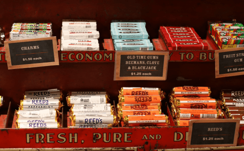A vintage candy display featuring various gum and candy bars with price tags.
