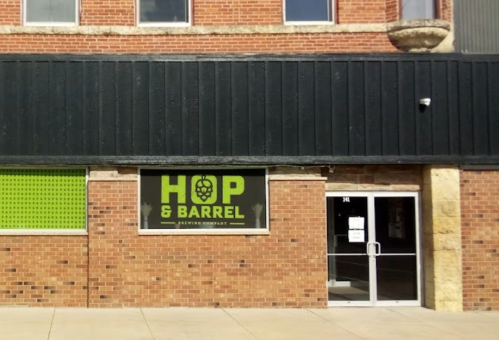 Exterior of Hop & Barrel Brewing Company, featuring a large sign and a brick facade.