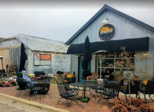 Exterior of Karst Brewing with outdoor seating, patrons, and autumn decorations on a cloudy day.