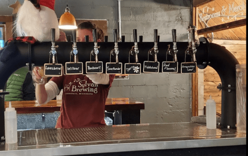 A bartender serves beer from a tap system with multiple handles at Sylvan Brewing in Lancaster, Minnesota.