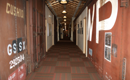 A long hallway with vintage train car walls, featuring industrial decor and dim lighting.