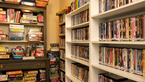 A cozy room with shelves of DVDs and a cabinet filled with board games.