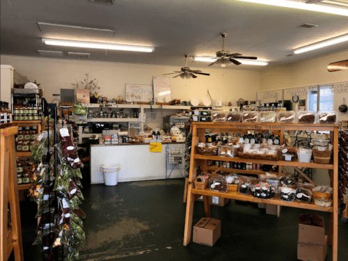 A cozy store interior with shelves of jars, snacks, and baked goods, featuring wooden displays and a welcoming atmosphere.