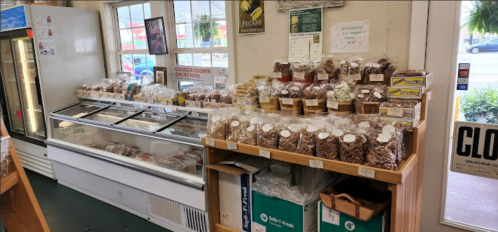 A cozy store interior featuring a display of packaged snacks and a glass case filled with various treats.