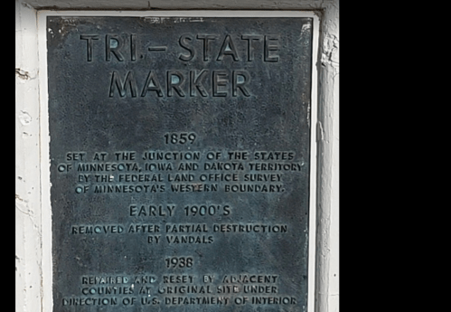 A weathered plaque detailing the Tri-State Marker, established in 1859 at the junction of Minnesota, Iowa, and Dakota Territory.
