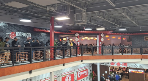 A bustling hot pot restaurant with diners on a balcony and a lively atmosphere.