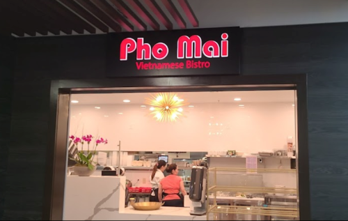 Sign for "Pho Mai" Vietnamese Bistro, featuring a modern interior and staff preparing food in the background.