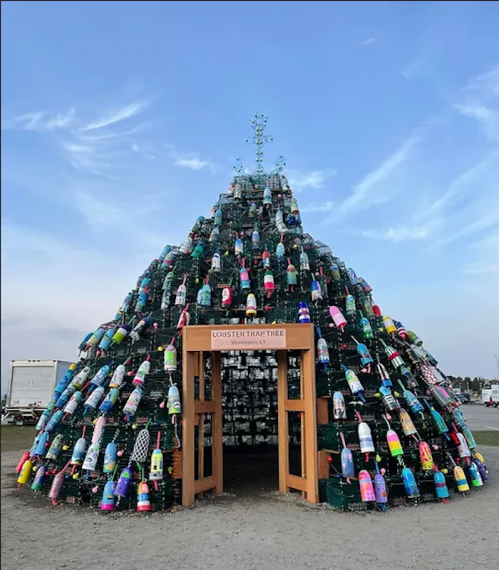 A festive tree made of colorful lobster traps and buoys, with a wooden sign reading "Lobster Trap Tree."