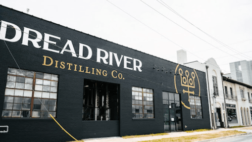 Exterior of Dread River Distilling Co. building, featuring a large sign and industrial windows.