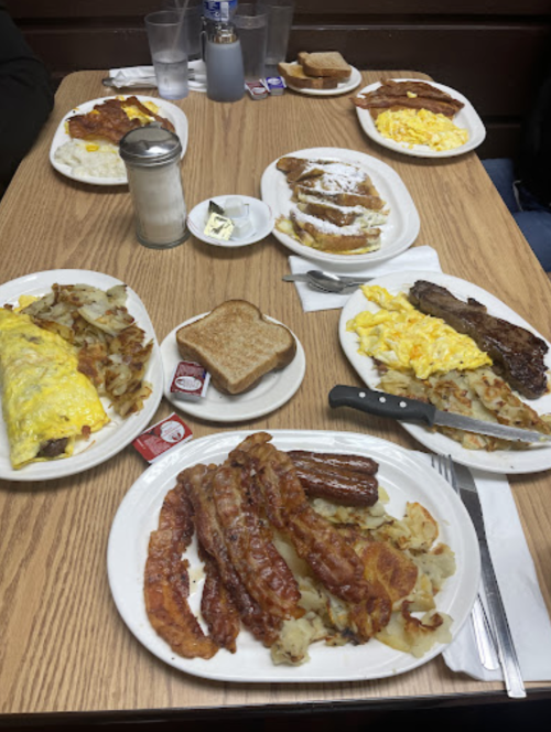 A table with multiple plates of breakfast food, including omelets, bacon, eggs, toast, and hash browns.