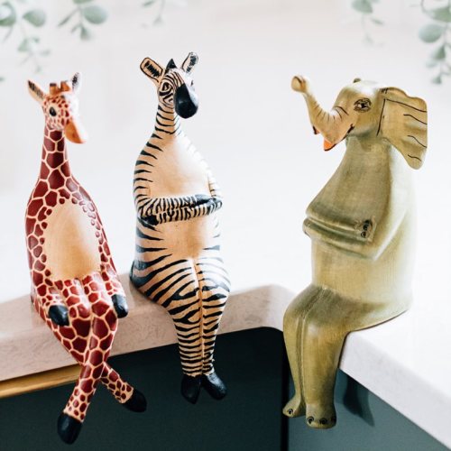 Three whimsical animal figurines: a giraffe, a zebra, and an elephant, sitting on a countertop.