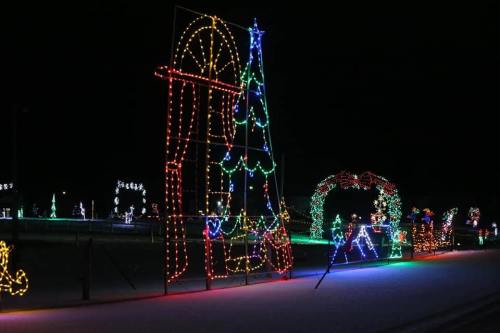 Colorful holiday lights display featuring a large tree, arch, and various festive shapes against a dark night sky.