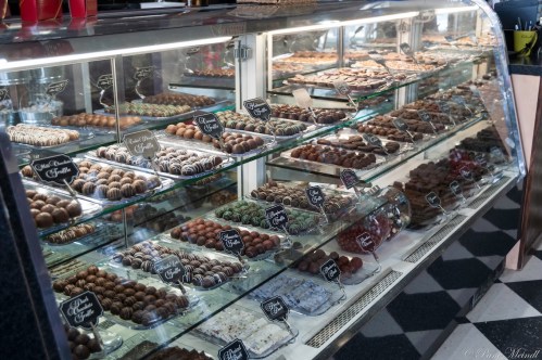 A display case filled with various types of chocolates and confections, neatly arranged with labels.