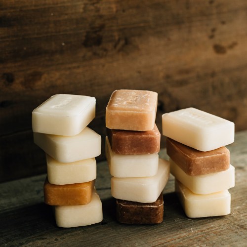 A stack of various colored soap bars arranged on a wooden surface.