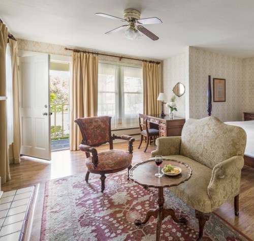 Cozy hotel room with a seating area, a small table with snacks, and a view of a balcony through open doors.