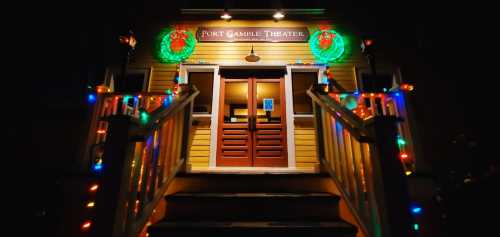 Entrance of Port Gamble Theater adorned with festive lights and wreaths, illuminated at night.