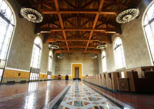 Interior of a spacious hall with wooden beams, large windows, and decorative tile flooring.
