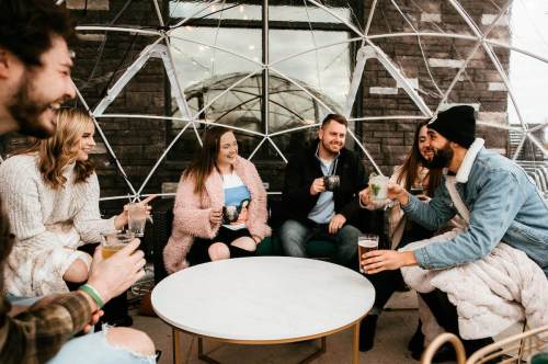 A group of friends enjoying drinks together in a cozy, modern setting with a unique dome structure.