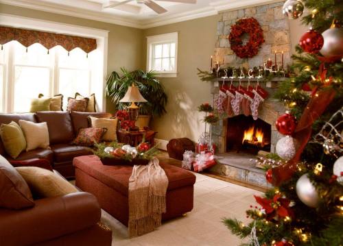 Cozy living room decorated for the holidays, featuring a fireplace, stockings, and a Christmas tree with ornaments.