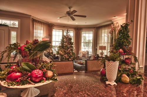 A cozy living room decorated for the holidays, featuring a Christmas tree and festive arrangements on a countertop.