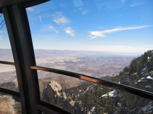 View from a gondola overlooking a vast mountainous landscape and clear blue sky.