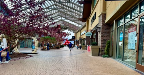 Looking down a large walkway at Outlets at Traverse Mountain with holiday decorations lining the middle and a glass ceiling overhead.