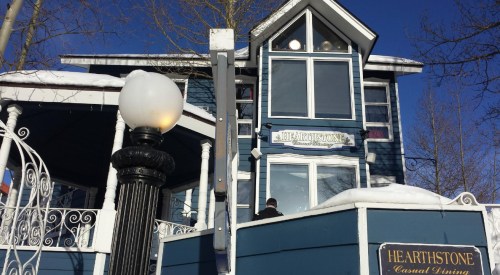 A blue building with white trim and a sign reading "Hearthstone Casual Dining," surrounded by snow and a lamp post.