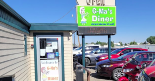 Exterior of G-Ma's Diner with a sign advertising "Tuesday Spaghetti" and parked cars in front.