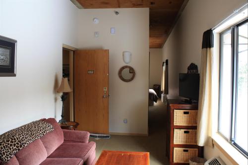 Cozy interior of a room featuring a sofa, wooden table, wall clock, and a view of a hallway with a door.