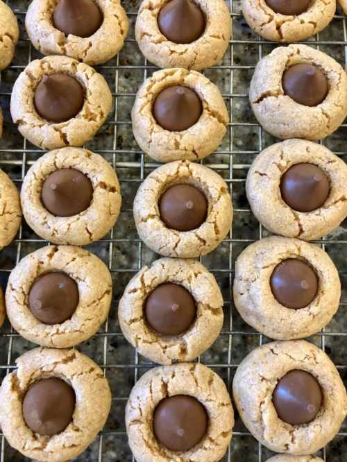 A close-up of freshly baked cookies with a chocolate candy in the center, arranged on a cooling rack.