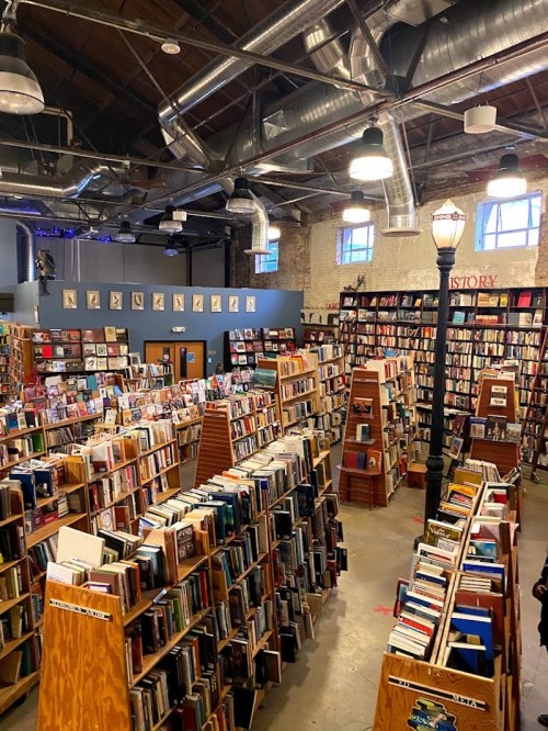 A spacious bookstore filled with tall bookshelves, cozy reading areas, and warm lighting, creating an inviting atmosphere.