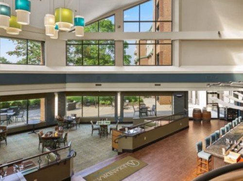 Bright, modern restaurant interior with large windows, stylish lighting, and a view of outdoor seating.