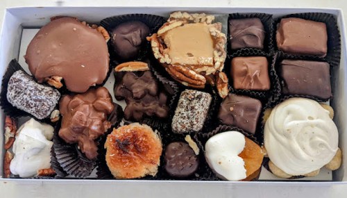 A variety of chocolates and confections arranged in a box, including caramel, nuts, and cream-filled treats.