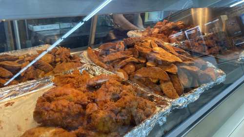 A display case filled with crispy fried chicken and golden-brown potato wedges.
