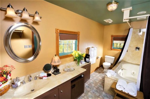A cozy bathroom featuring a whirlpool tub, sink, and decorative lighting, with flowers and towels arranged neatly.