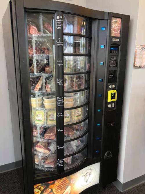 A vending machine filled with various meats and snacks, featuring clear glass doors and labeled compartments.