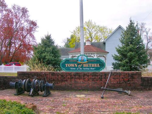 Sign for the Town of Bethel, featuring historical cannons and greenery in the background.