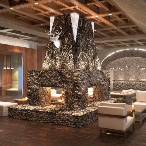 A modern lounge with a large stone fireplace, featuring a deer head mount and cozy seating arrangements.