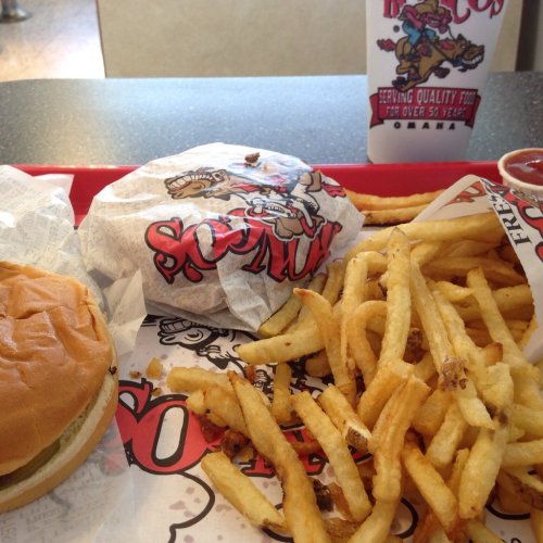 A tray with a burger, wrapped sandwich, fries, and a drink from a fast-food restaurant.